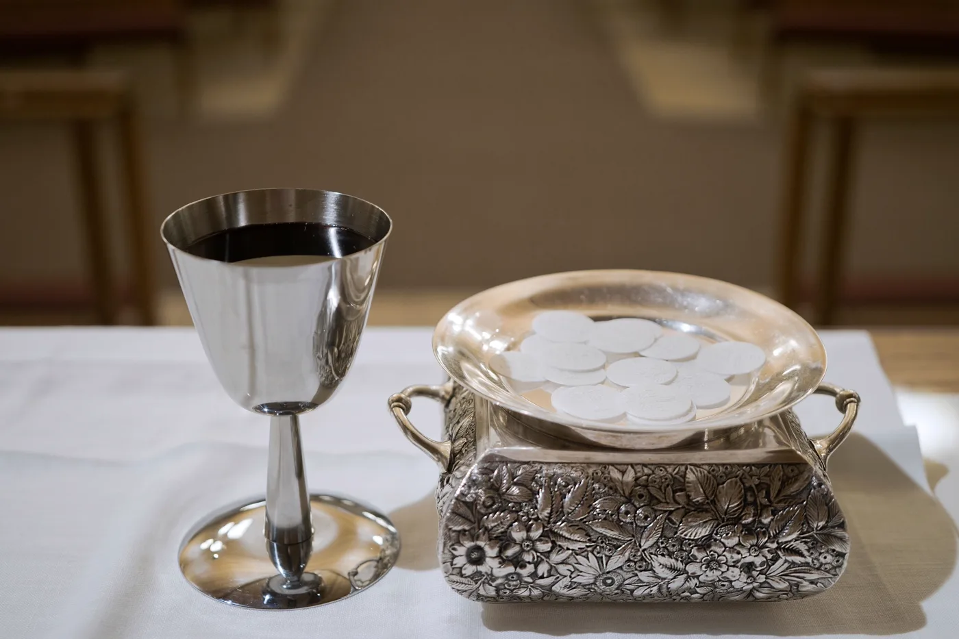 A silver chalice and paten with communion wafers prepared for the Eucharist