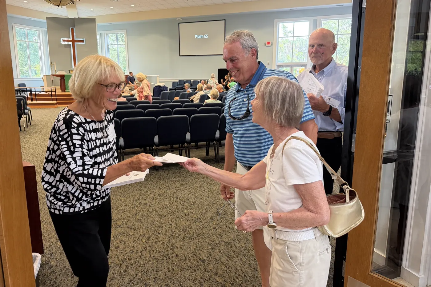 A greeter handing a bulletin to arriving members at Christ Church Bluffton