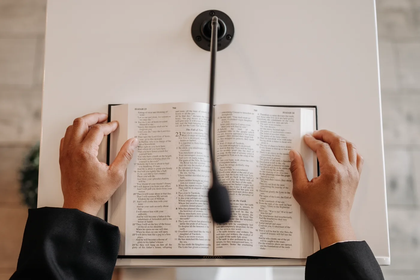 Hands holding an open Bible at a lectern during a reading