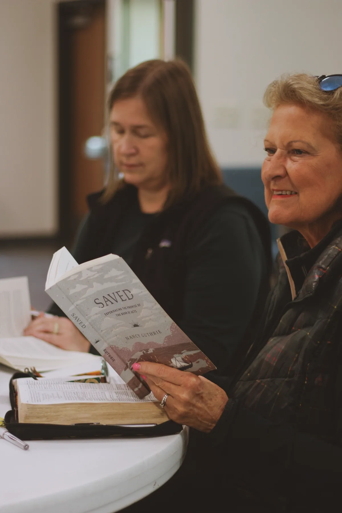 Women gathered around a table studying scripture together in prayerful fellowship